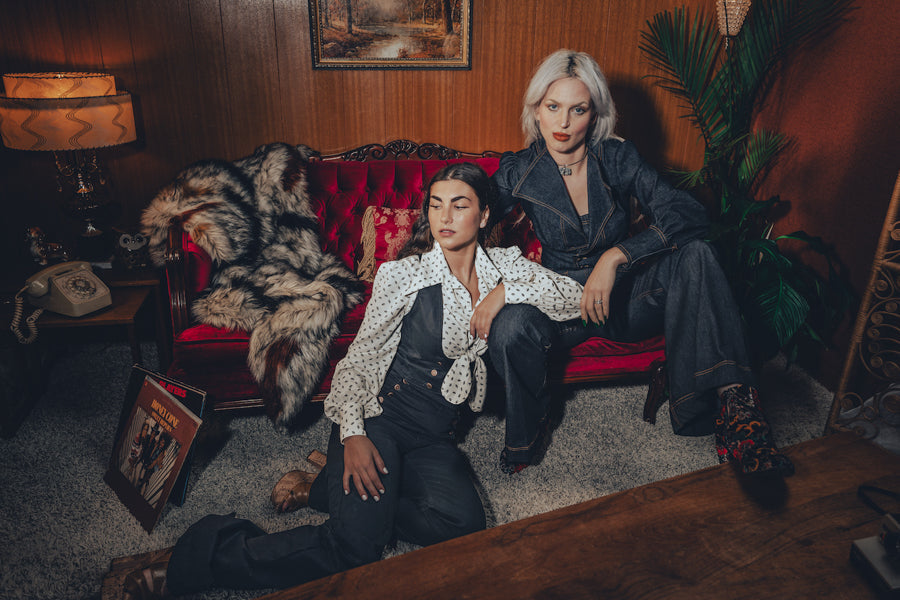 Two groovy chicks in the 1970s lounge wearing cool and classy 70s inspired outfits capturing retro style and vintage elegance