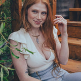 Woman with red hair sitting outdoors on wooden steps surrounded by plants