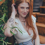 Woman with red hair sitting outdoors among plants