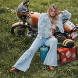 Woman sitting on a suitcase next to a motorcycle in a grassy field wearing Soul Sister since 1969