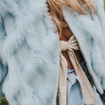 Person wearing a light blue fur coat with a neutral background wearing Soul Sister since 1969
