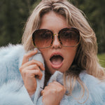 Person wearing sunglasses and a light blue fur coat with a blurred natural background wearing Soul Sister since 1969