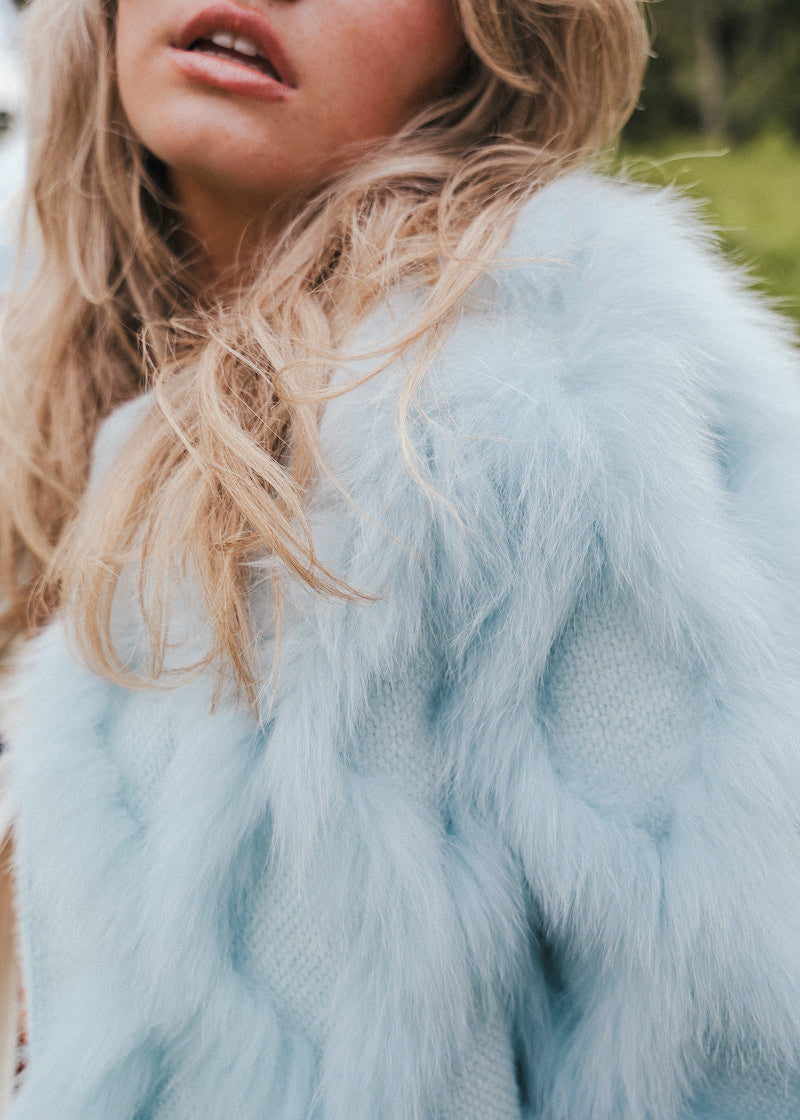 Close-up of a person wearing a light blue fur coat with blurred background wearing Soul Sister since 1969