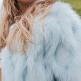 Close-up of a person wearing a light blue fur coat with blurred background wearing Soul Sister since 1969