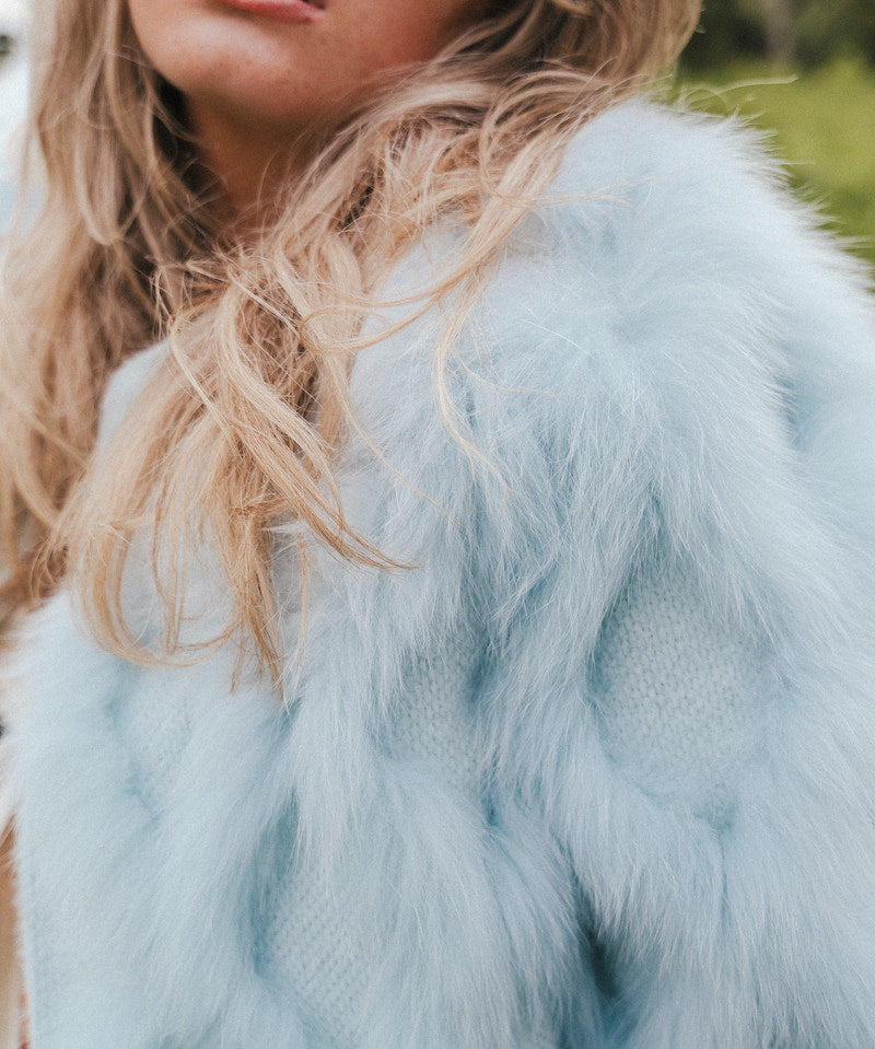 Close-up of a person wearing a light blue fur coat with blurred background wearing Soul Sister since 1969