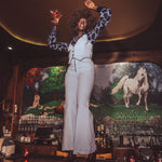 Person in a stylish outfit standing in a bar with horse painting in the background