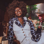 Woman in a stylish outfit holding a cocktail in a bar setting