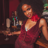 Woman in a sexy red  1970s inspired velvet outfit holding a cocktail at a retro speakeasy bar.