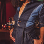 Woman wearing a denim 70s jumpsuit with a blurred bar setting in the background