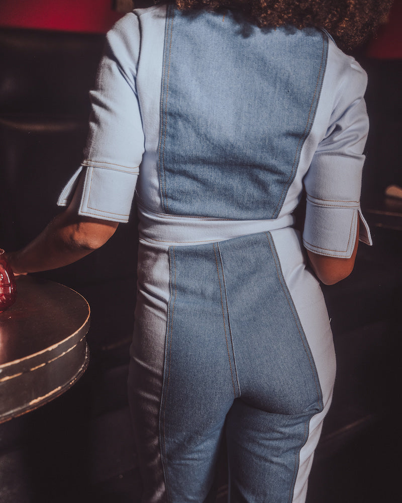 Person wearing a denim and white outfit in a dark setting