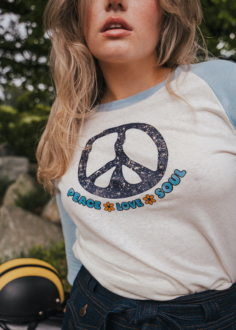 Person wearing a shirt with a peace symbol and text outdoorsWoman wearing a peace symbol shirt with text outdoors wearing Soul Sister since 1969