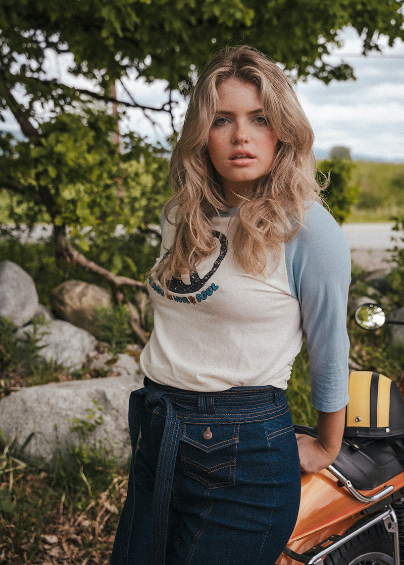Woman standing outdoors with a scenic background wearing Soul Sister since 1969.
