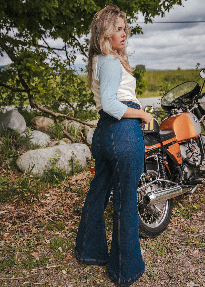 Woman standing next to a motorcycle in a natural setting wearing Soul Sister since 1969.