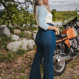 Woman standing next to a motorcycle in a natural setting wearing Soul Sister since 1969.