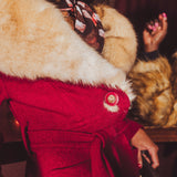 Close-up of a person wearing a red vintage inspired 1970s coat with fur trim and a floral scarf.