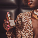 Woman in leopard print outfit holding a perfume bottle with a dark background