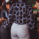 Person wearing a funky 1970s style retro shirt and light blue bell bottom jeans in a studio '54 setting