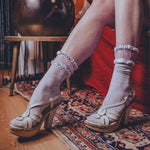 Person wearing white sandals with wooden soles on a patterned rug.