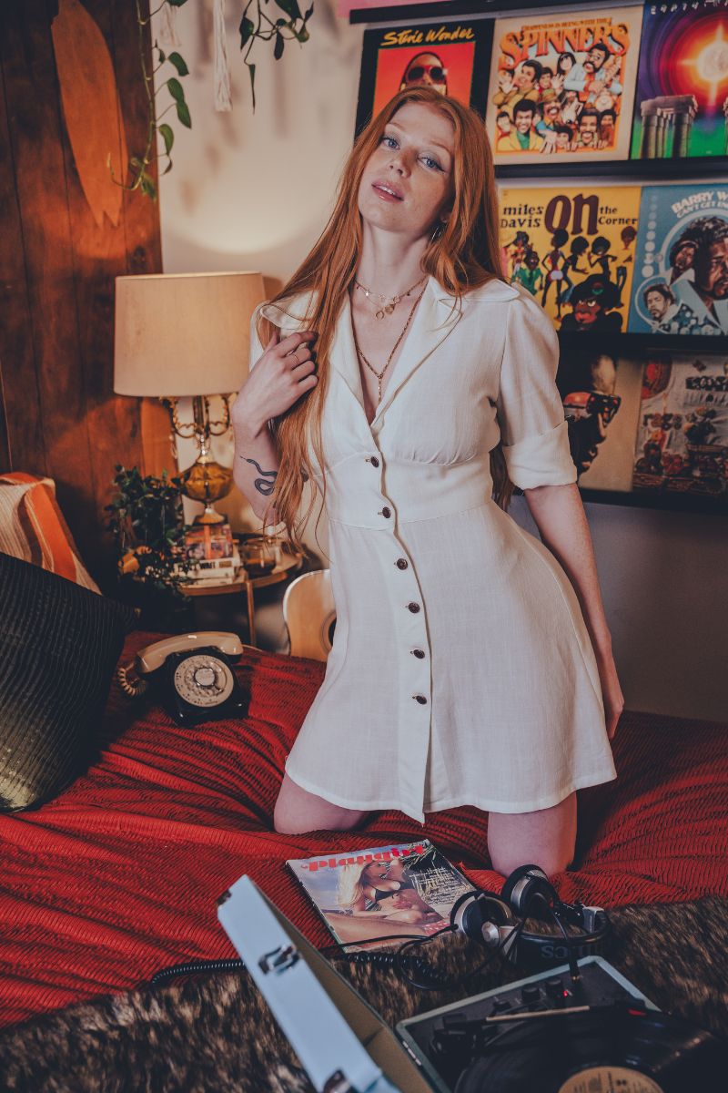 Woman in a white dress standing in a room with posters on the wall