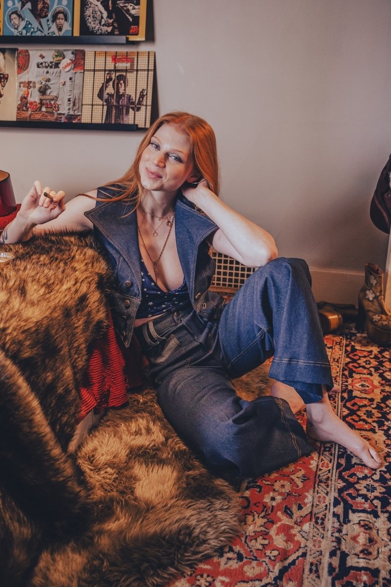 Woman sitting on a couch in a room with posters on the wall