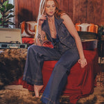 Woman sitting on a red couch in a room with wooden walls and decorative items.