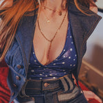 Person wearing a blue denim outfit with a deep neckline and layered necklaces.
