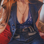 Woman wearing a denim vest over a star-patterned top with a blurred background
