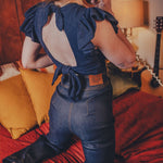 Person wearing a blue top with ruffled sleeves in a bedroom setting.