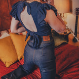 Person wearing a blue top with ruffled sleeves in a bedroom setting.