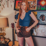 Person standing in a room with vinyl records and a guitar