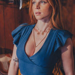 Woman wearing a blue top with ruffled shoulders in a rustic setting