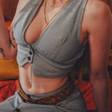 Person wearing a faded denim 70s inspired waistcoat  with a woodstock inspired floral belt in a warm-toned  1970s setting