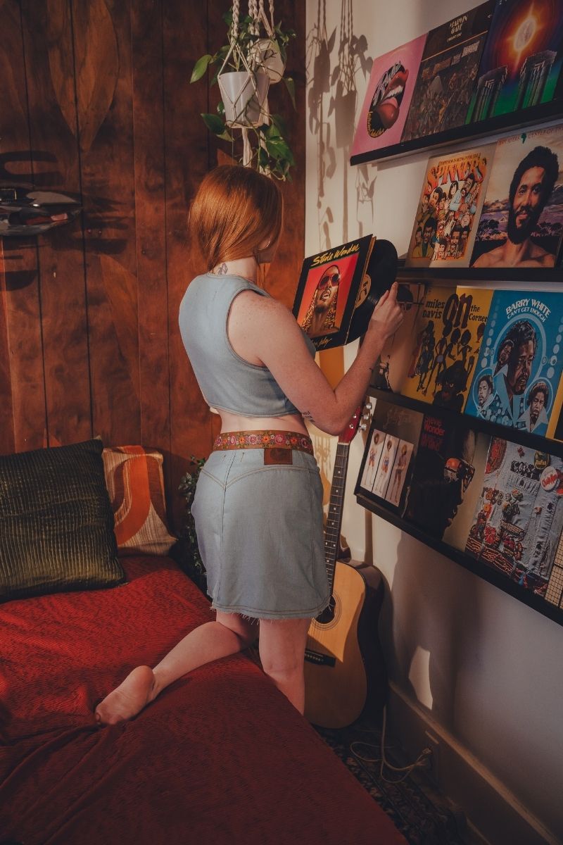Person in a room with 70s vinyl records and a guitar wearing Soul Sister since 1969 small batch clothing made in Vancouver Canada