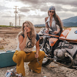Two women with a motorcycle in an outdoor setting wearing Soul Sister since 1969