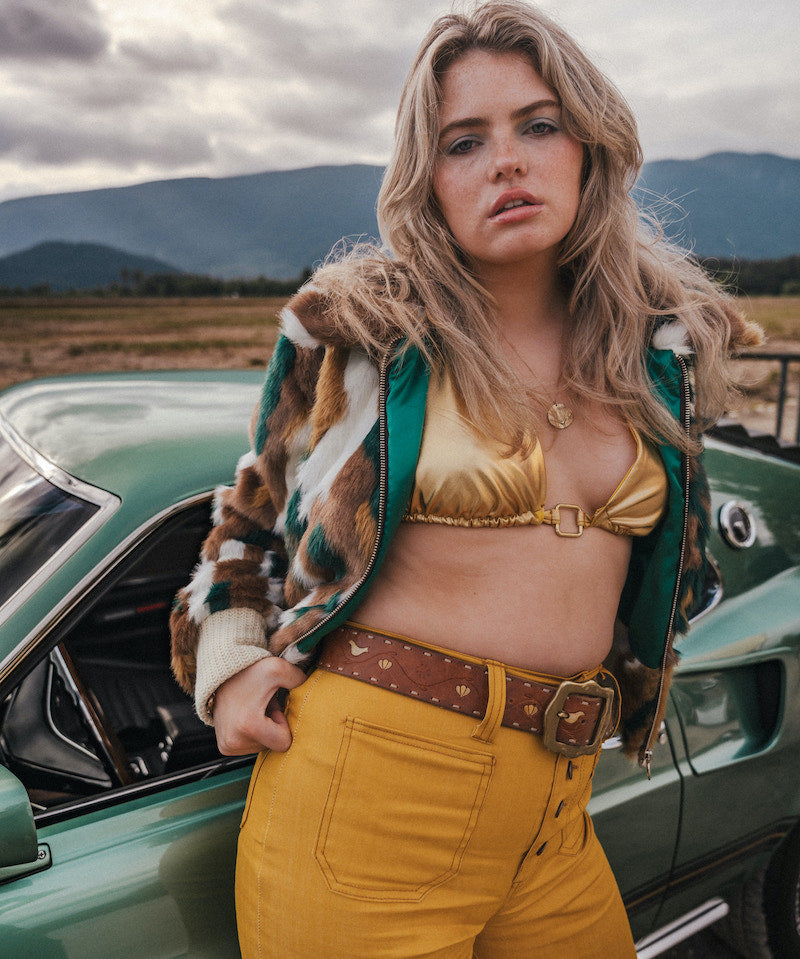 Woman in a vintage outfit standing next to a classic car with mountains in the background wearing soul sister since 1969
