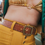 Person wearing a gold top and yellow pants with a brown belt wearing soul sister since 1969.