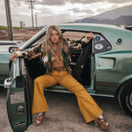 Woman sitting in the driver's seat of a vintage car with mountains in the background wearing Soul Sister since 1969