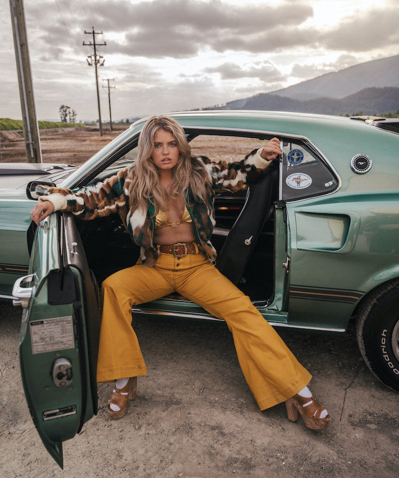 Woman sitting in the driver's seat of a vintage car with mountains in the background wearing Soul Sister since 1969