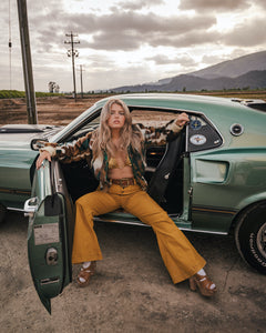Woman sitting in a vintage car with a scenic background wearing soul sister since 1969