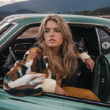 Woman sitting in a vintage car with mountains in the background wearing Soul Sister since 1969