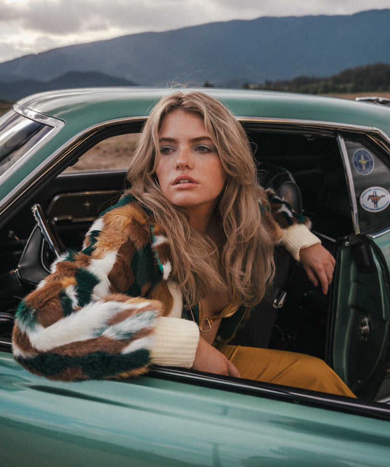 Woman sitting in a vintage car with mountains in the background wearing Soul Sister since 1969