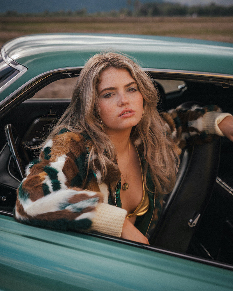 Woman sitting in a vintage car with a scenic background 
