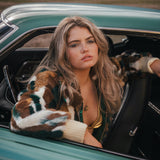 Woman sitting in a vintage car with a scenic background 
