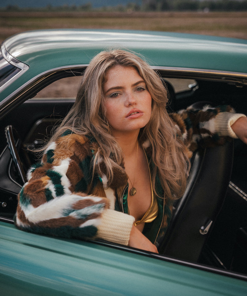 Woman sitting in a vintage car with a scenic background 

