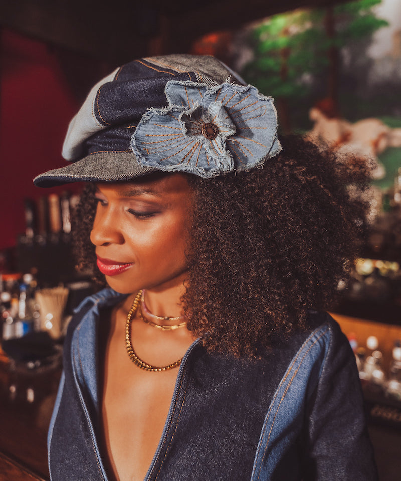 Woman wearing a denim cap with a flower accessory in a bar setting