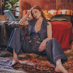 Woman sitting on a rug in a cozy living room with a laptop.