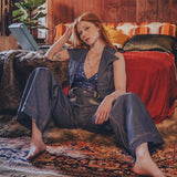 Woman sitting on a rug in a cozy living room with a laptop.