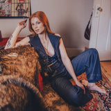 Woman sitting on a fur-covered couch in a room with posters on the wall.
