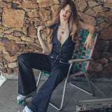a woman sits in a chair wearing roller skates in a '70s style sexy denim jumpsuit wearing an agate gold necklace by soul sister since 1969
