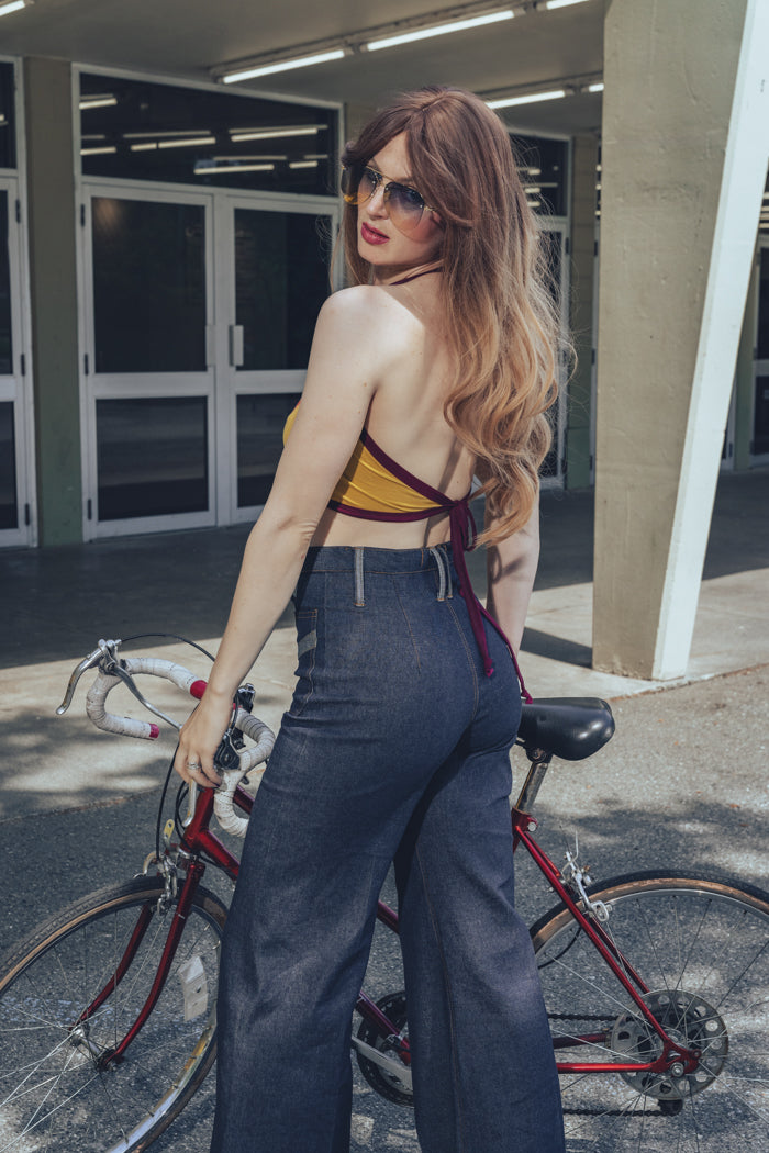 Girl at the roller skate park  in denim bell bottoms a yellow halter top and a red 10 speed bike wearing retro 70s bellbottoms
